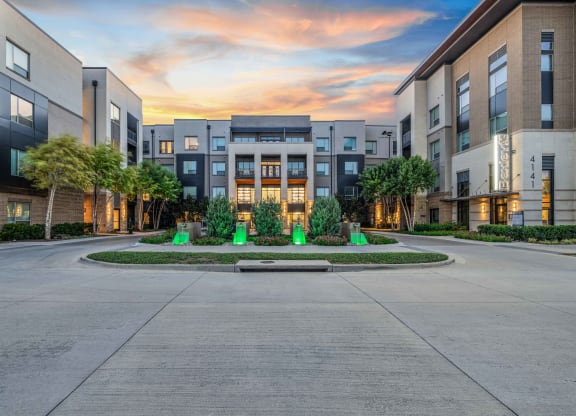 an empty street in front of an apartment building at sunset