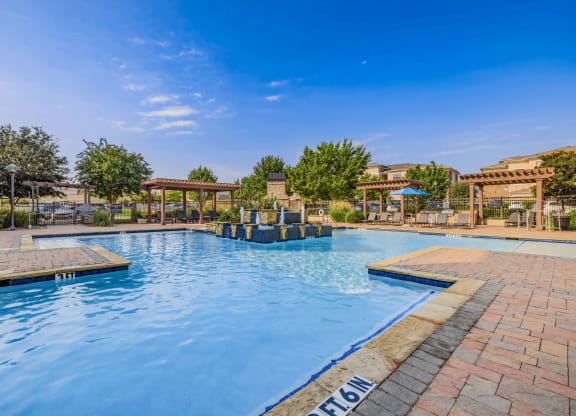 a swimming pool with trees and a blue sky above it