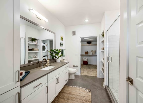 a bathroom with white cabinets and a shower and a sink