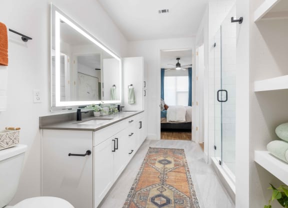 a white bathroom with a large mirror and a rug