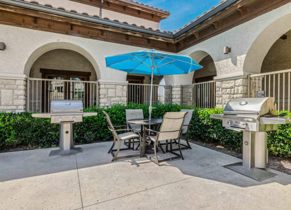 a patio with two bbq grills and a table and chairs