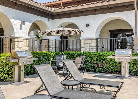 A patio with chairs, tables, and grills is set up outside a building.