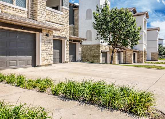 A row of houses with garages and a tree in front.