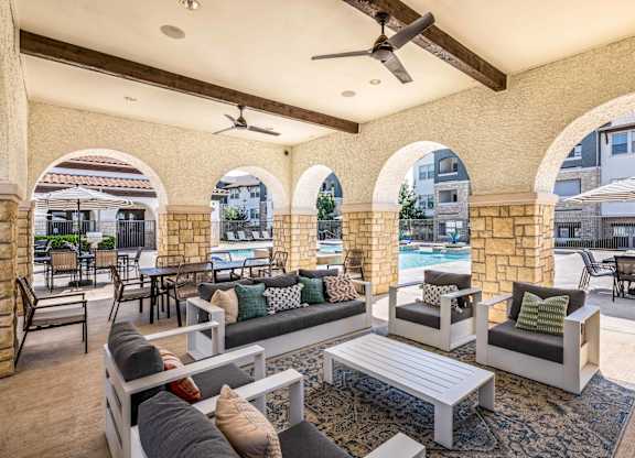 A patio with a pool and a table with chairs.