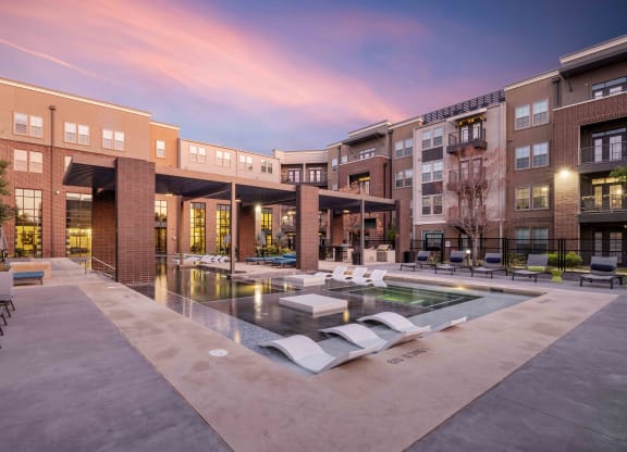a pool with lounge chairs in front of a building