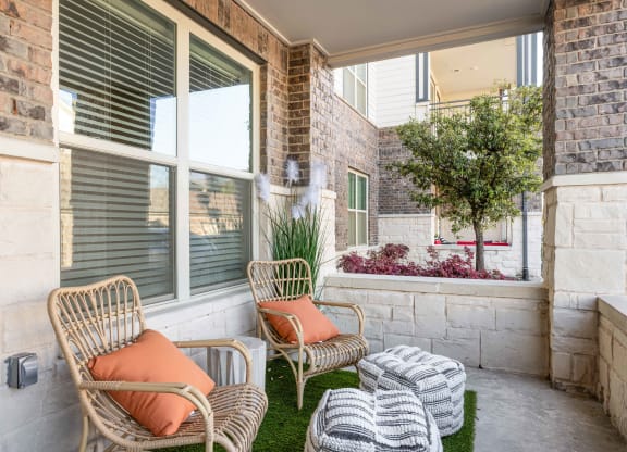 a porch with two chairs and a table and a window