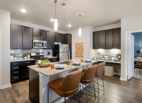 a kitchen with a large island with chairs and a counter top