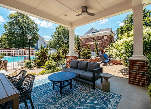 A patio with a table and chairs and a pool in the background.