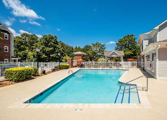 A swimming pool surrounded by a fence and trees.