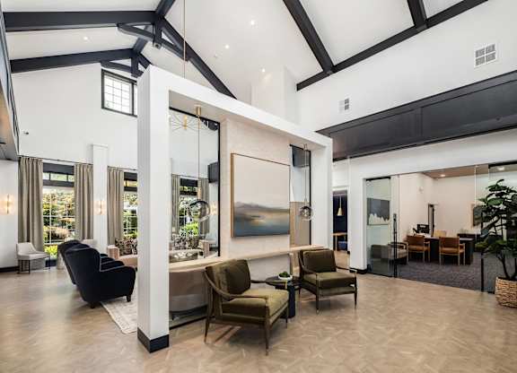 A spacious living room with a large painting on the wall and a variety of seating options.