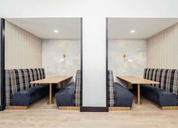 Two identical booths with plaid cushions and wooden tables.