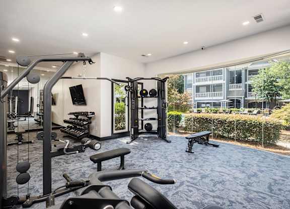 A gym with a variety of equipment including a weight bench, a leg press machine, and a cable machine.