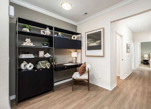A hallway with a chair and a shelf with decorations.