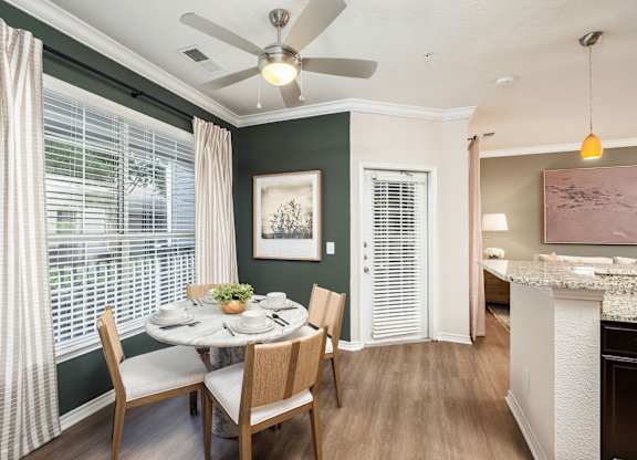 A dining room with a table set for four and a ceiling fan.