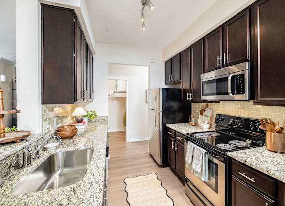 A kitchen with dark brown cabinets and a granite countertop.