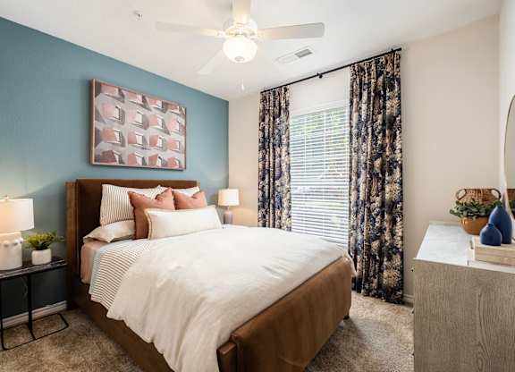 A bedroom with a large bed and a ceiling fan.