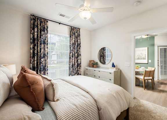 A bedroom with a bed, dresser, mirror, and chair.