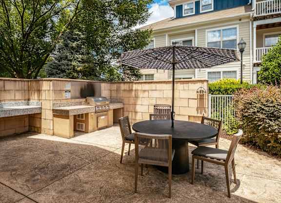 A patio with a table and chairs and a black umbrella.