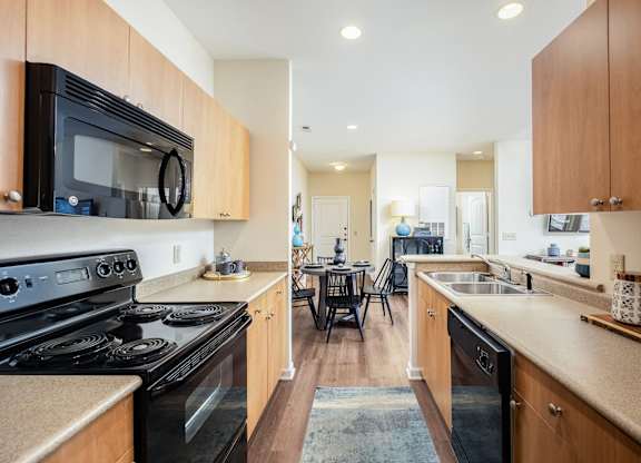 A kitchen with a black stove top oven and wooden cabinets.