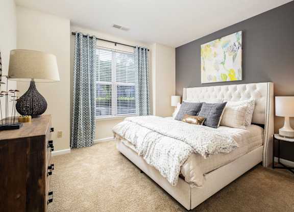 A bedroom with a large bed, a nightstand, and a lamp.