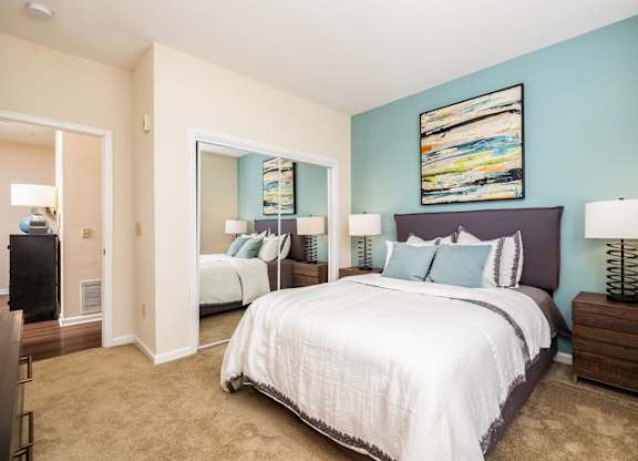 A bedroom with a large bed and a painting on the wall.