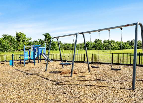 A playground with a swing set and a blue slide.