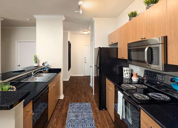 A kitchen with black countertops and wooden cabinets.