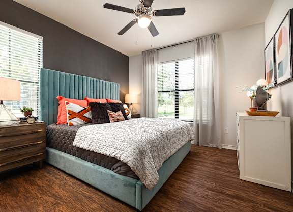 A bedroom with a bed, nightstand, and a ceiling fan.