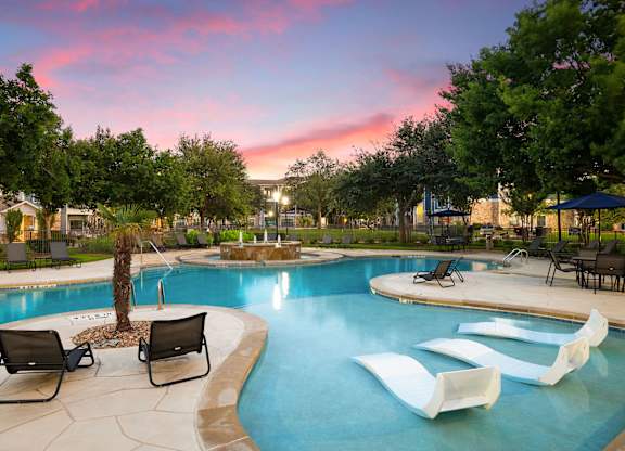 A pool area with a palm tree and lounge chairs.