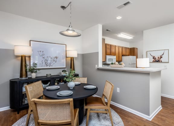 a dining area with a table and chairs and a kitchen in the background