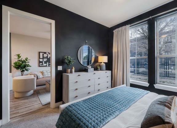 a bedroom with a bed and a dresser    and a large window