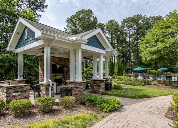 a pavilion with a stone fireplace and stone pillars