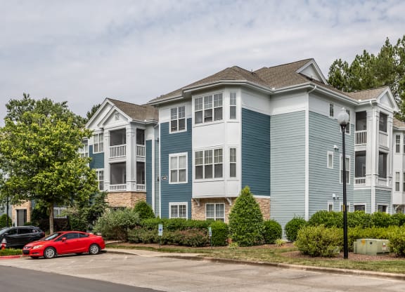 a blue and white apartment building with a red car parked in front of it