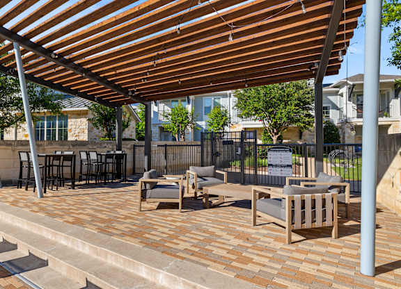 A patio with a wooden roof and furniture.