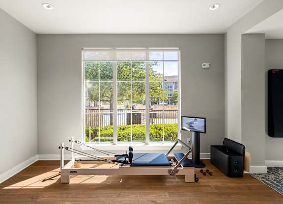 A room with a wooden floor and a row of windows.