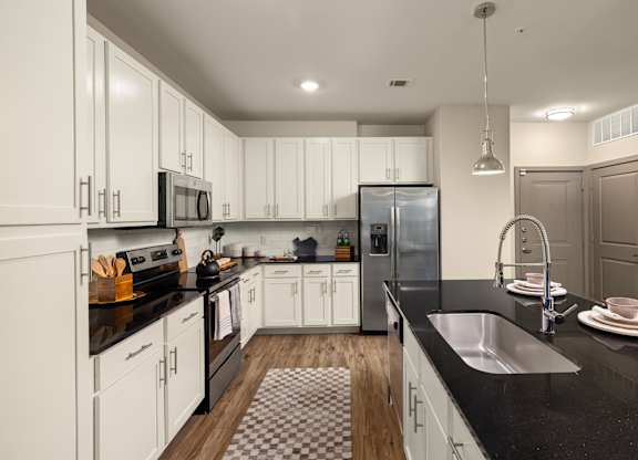 A modern kitchen with white cabinets and black countertops.