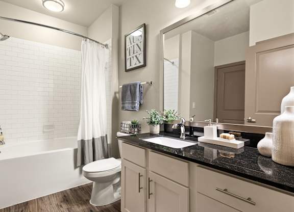 A bathroom with a white tub, sink, and toilet.