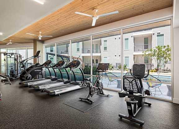 A gym with a variety of equipment including treadmills, elliptical machines, and weights.