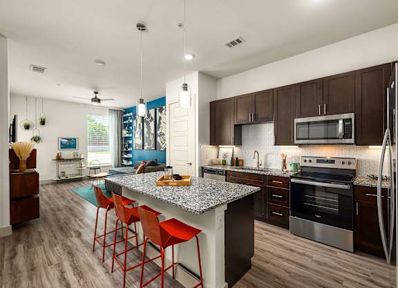 A kitchen with a large island and red barstools.