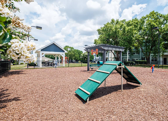 A playground with a green slide and a blue and white pavilion.