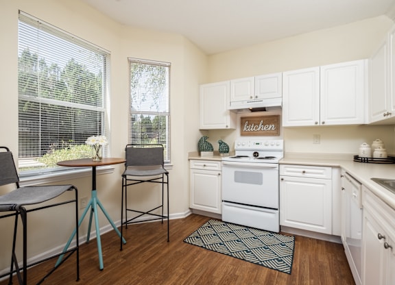 A kitchen with white cabinets and a wooden floor.