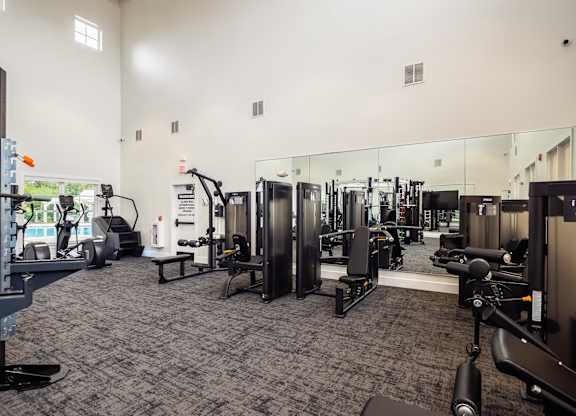 a gym with cardio equipment and mirrors on the wall