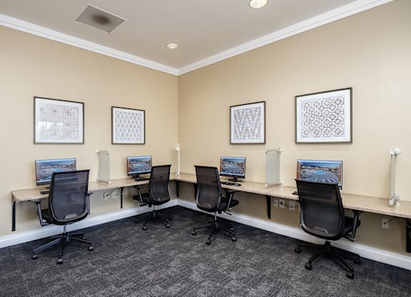 A room with a row of computers and chairs.