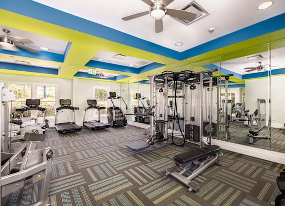 A gym with a variety of equipment including treadmills, weights, and exercise machines.