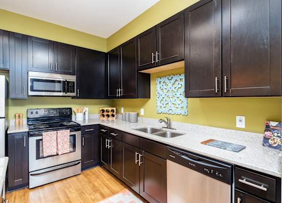 A kitchen with black cabinets and a stainless steel oven.