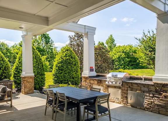 A patio with a table and chairs under a white pergola.