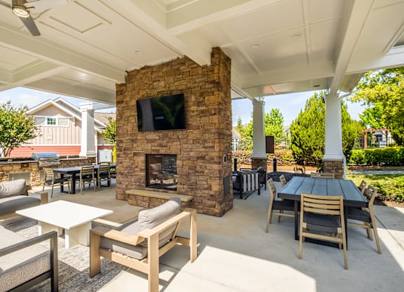 A patio with a stone fireplace and seating area.