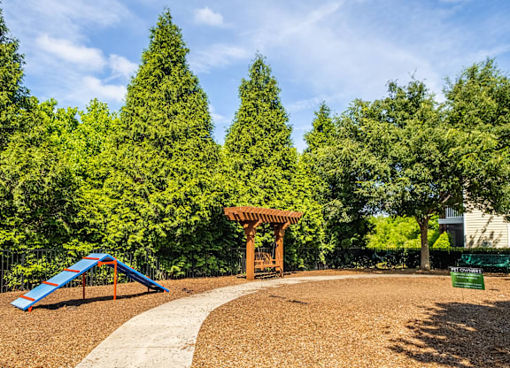 A playground with a blue slide and a wooden pergola.