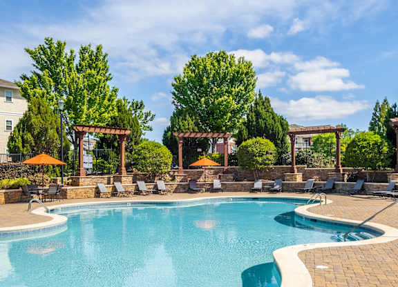 A large outdoor swimming pool surrounded by lounge chairs and umbrellas.