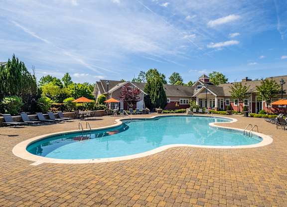 A large outdoor swimming pool surrounded by a brick patio.